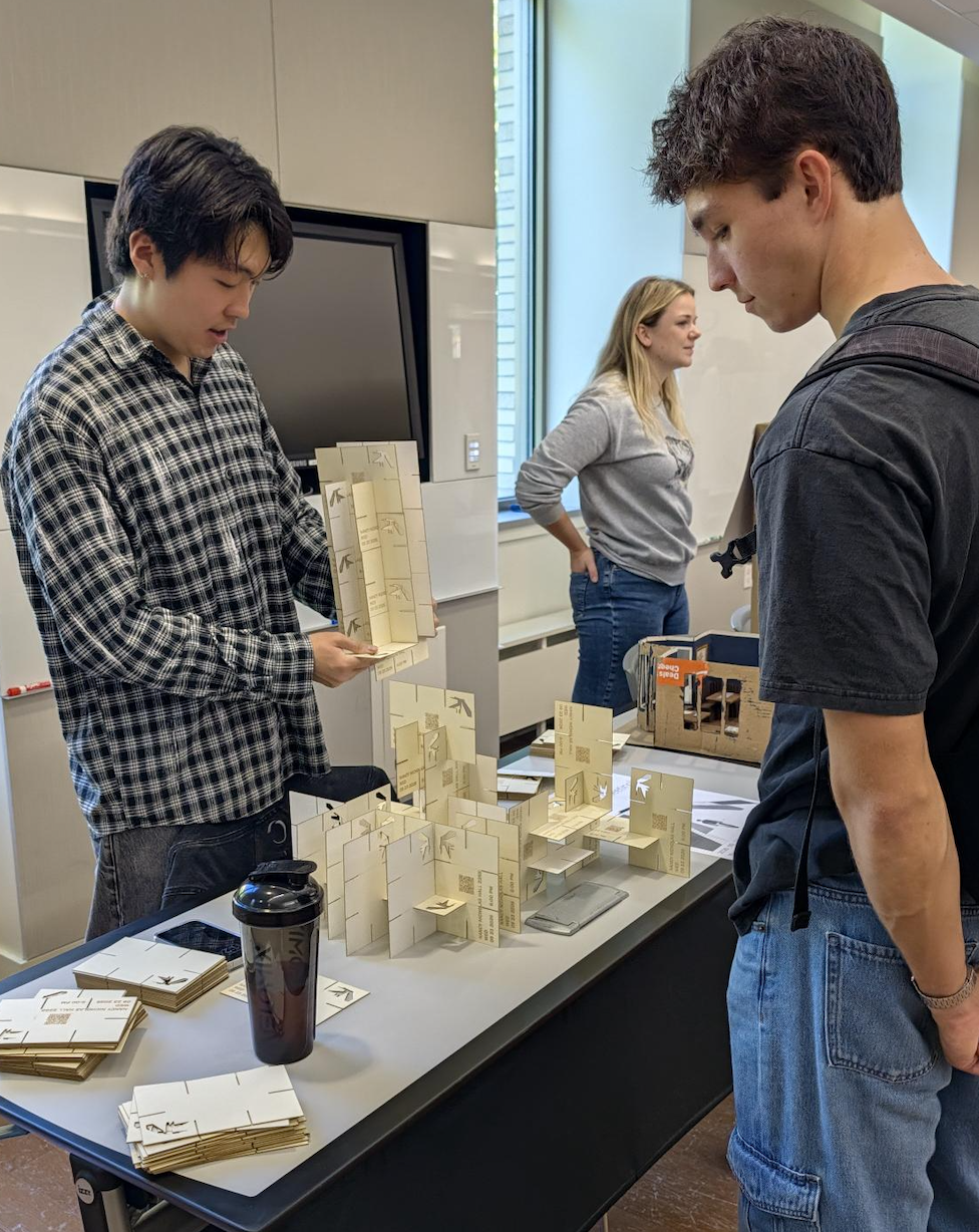 Drafting Room student showing another student 3D models on a table